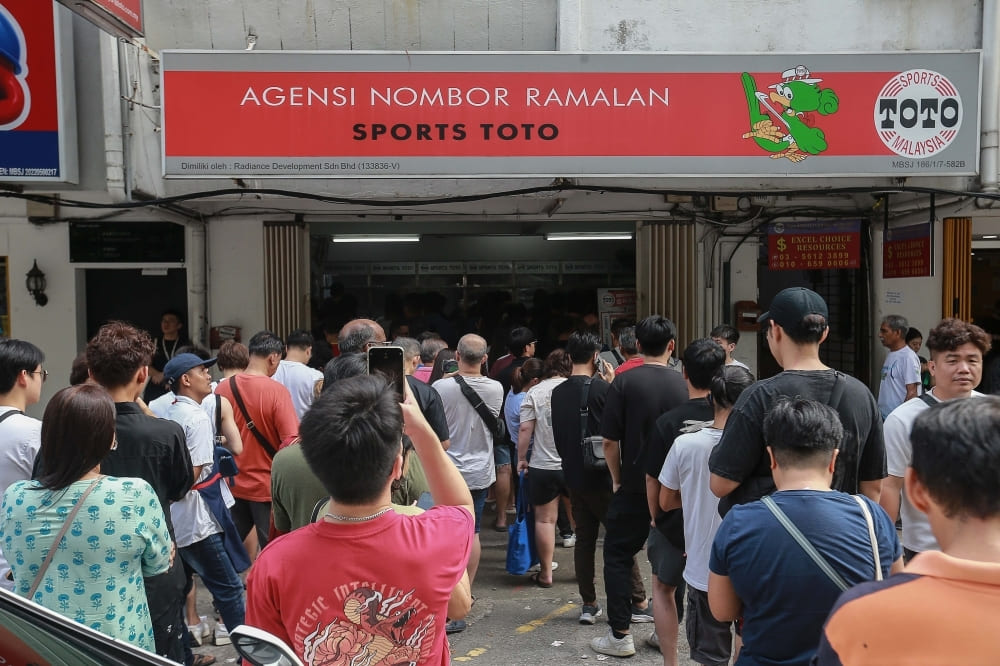 Orang ramai sedang beratur di luar sebuah kedai Sports Toto untuk membeli nombor loteri